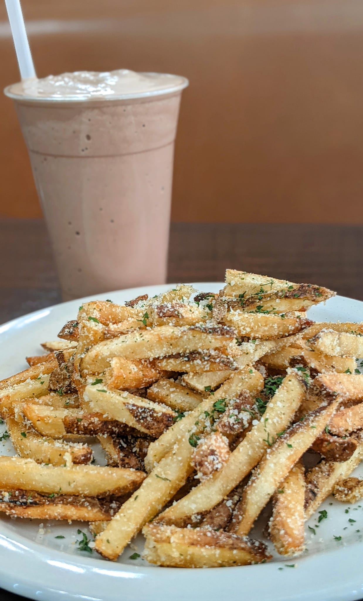 A plate of french fries and a milkshake on a table.