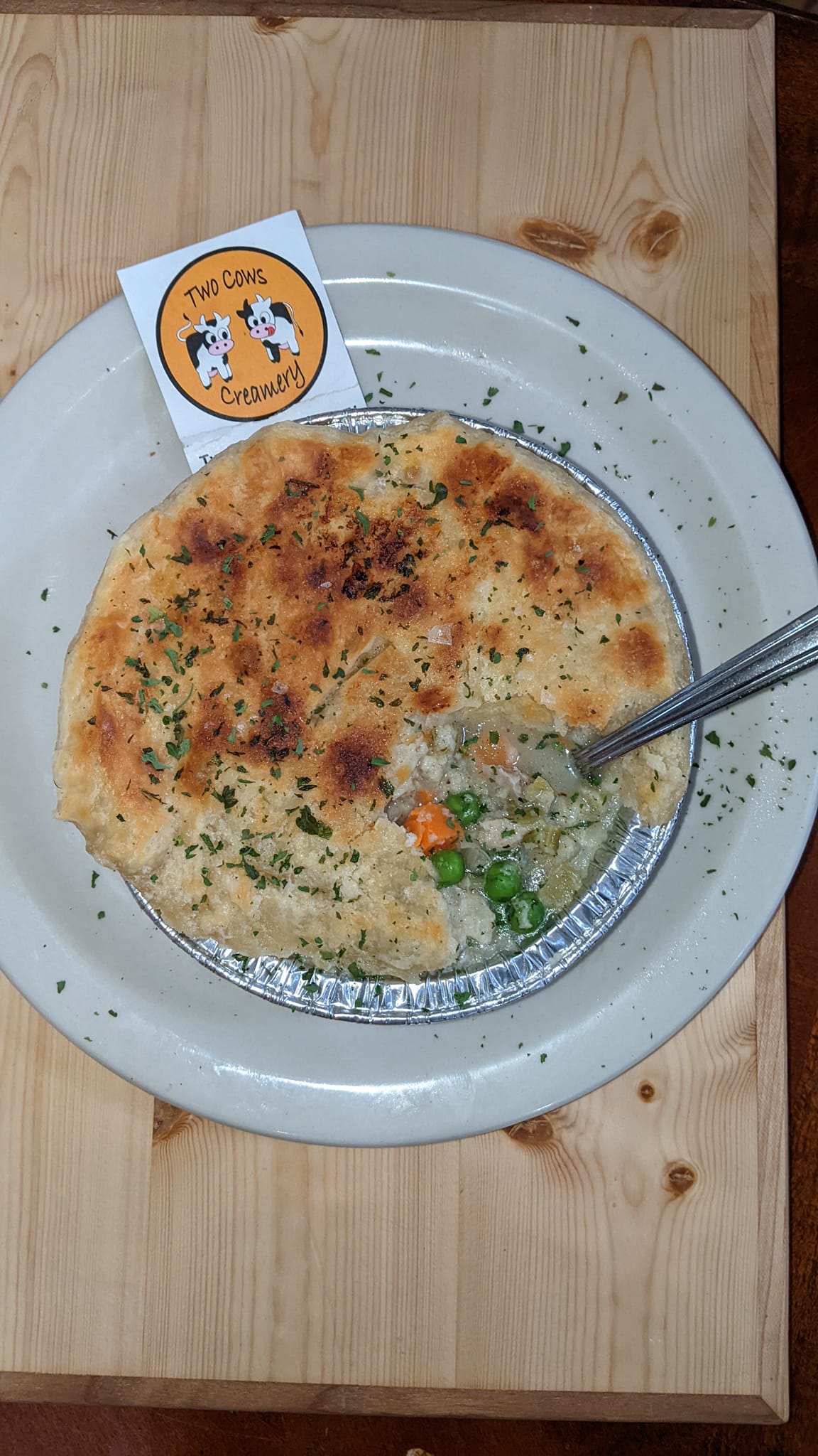 A pot pie with a spoon in it on a wooden table.