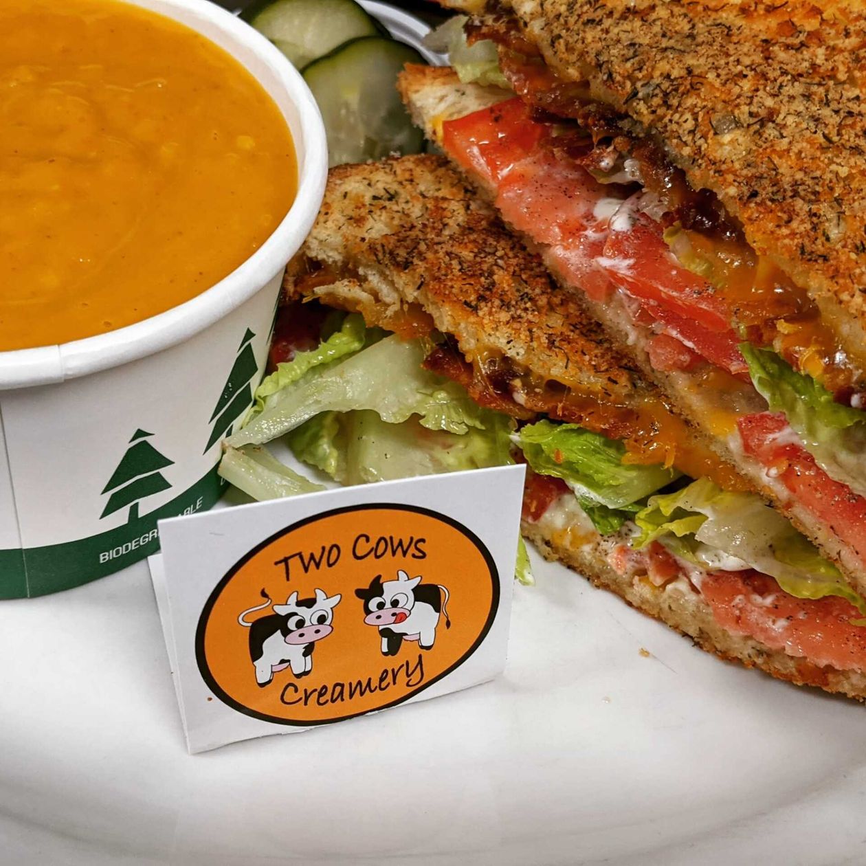 A sandwich and a cup of soup from two cows creamery