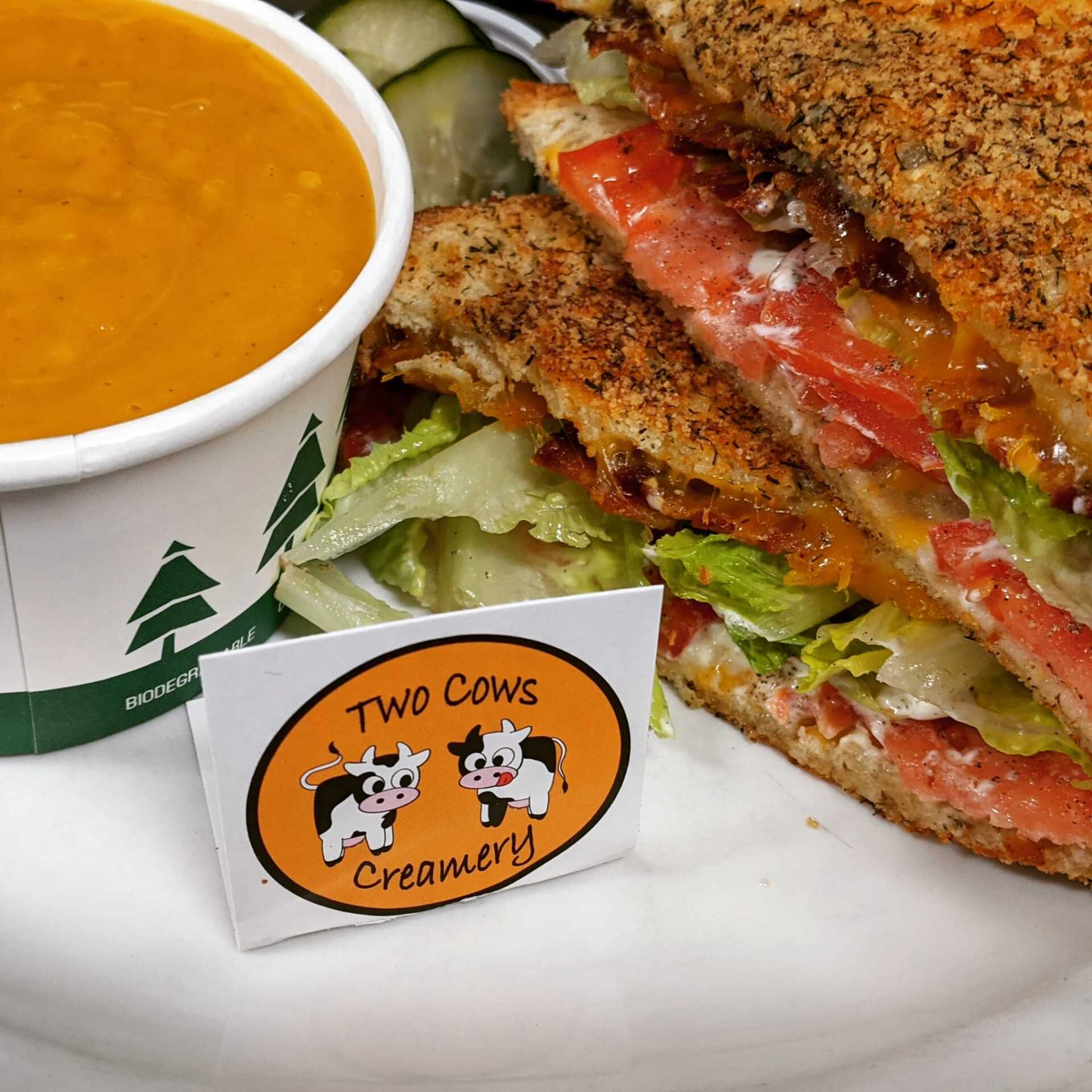 A sandwich and a cup of soup from two cows creamery