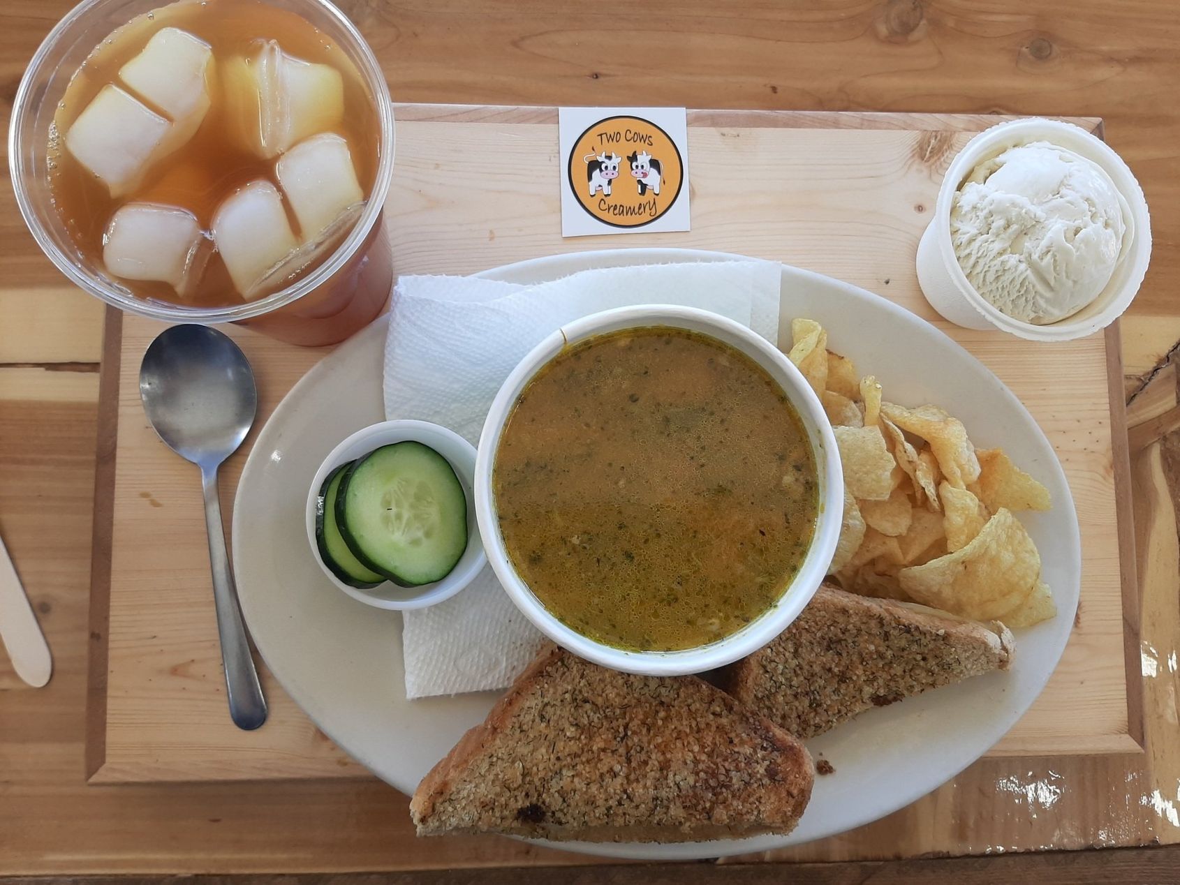 A plate of food with a bowl of soup and a cup of tea on a wooden table.