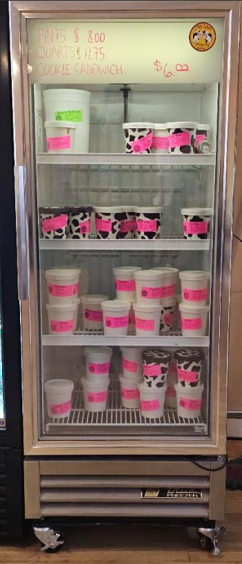 A refrigerator filled with lots of ice cream cups with purple labels.