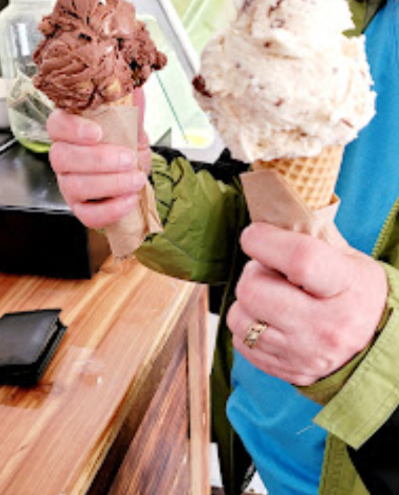 A person is holding two ice cream cones in their hands