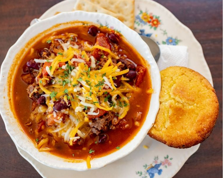 A bowl of chili next to a piece of bread