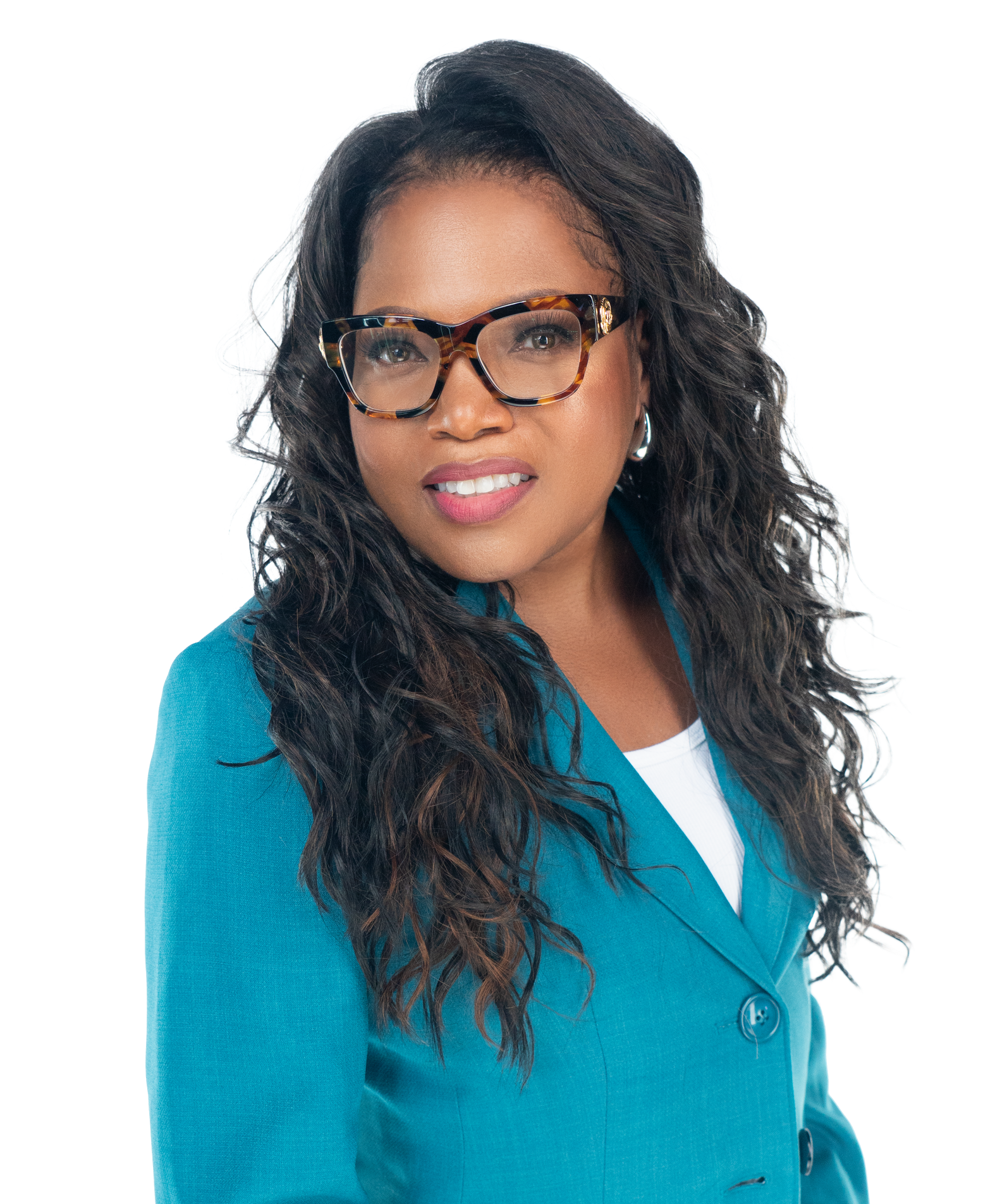 A person with long, dark, wavy hair wearing glasses and a teal blazer, smiling against a plain white background.