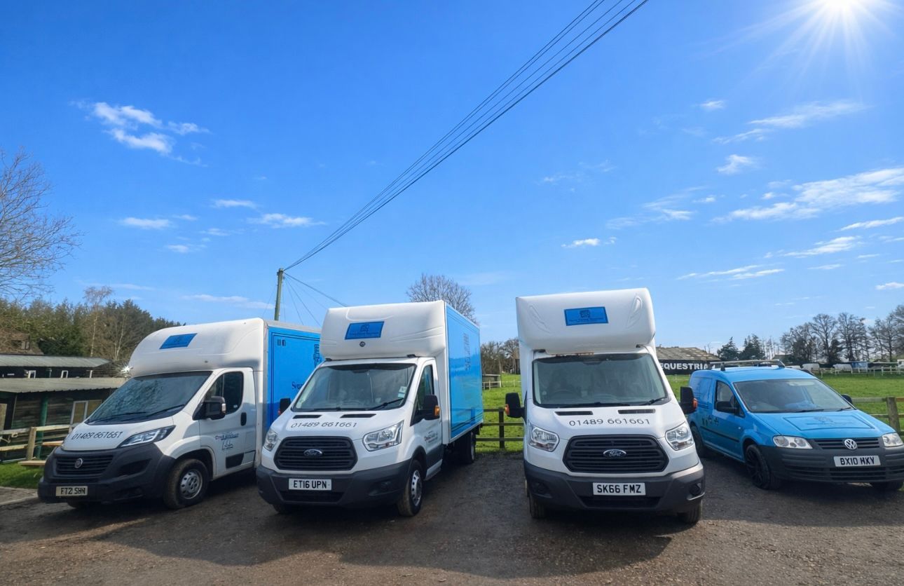 Four vans parked outside under a blue sky, two white vans with blue tops and a blue van.