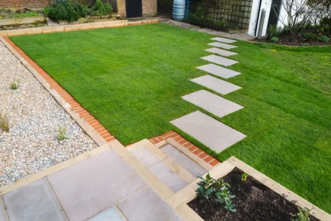 Backyard lawn with a diagonal stepping-stone path, stone patio, and gravel border