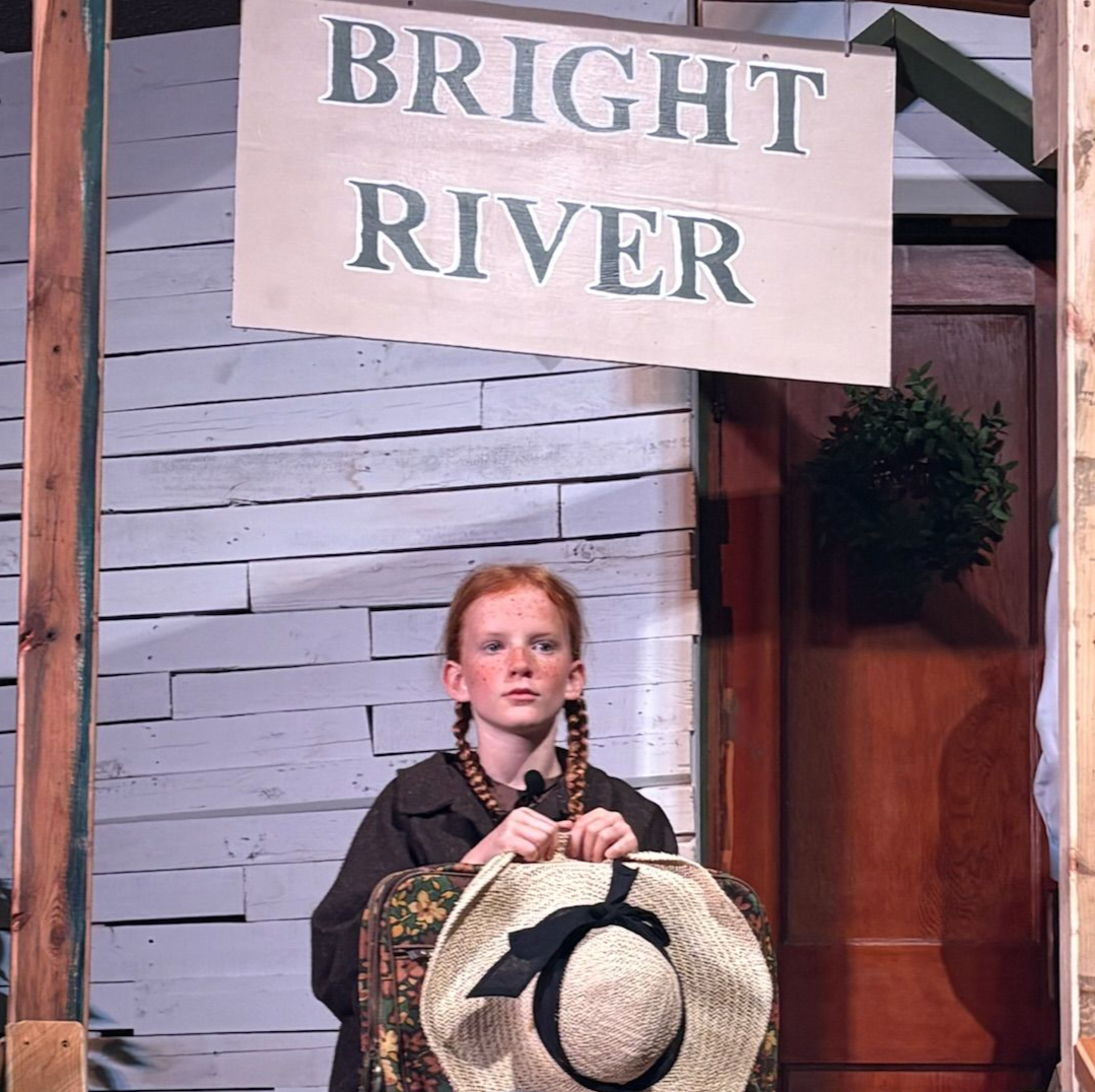 Woman holding a hat in front of a building sign reading “BRIGHT RIVER”