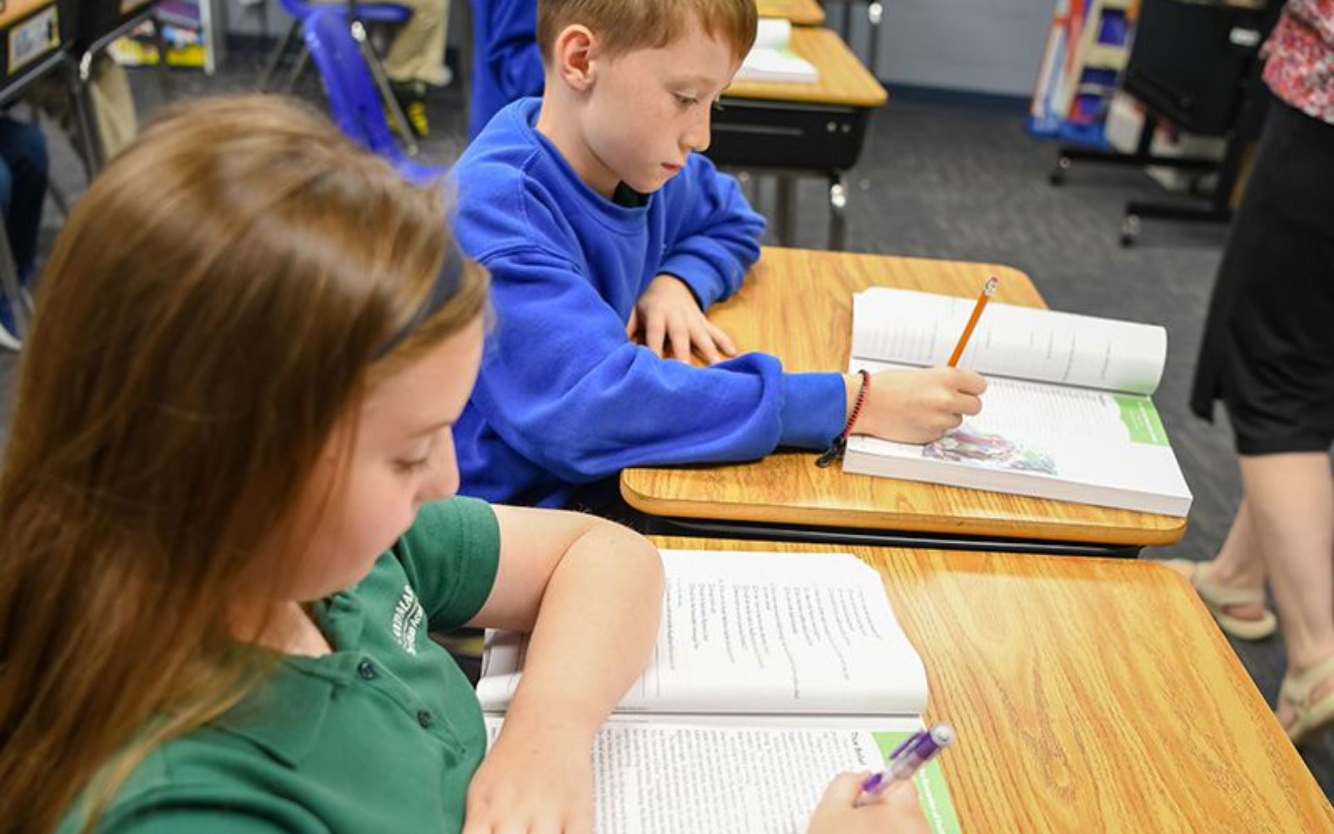 Students writing in notebooks at desks in a classroom
