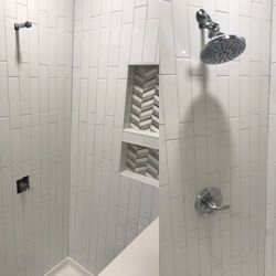 a bathroom with white tiles and a shower head