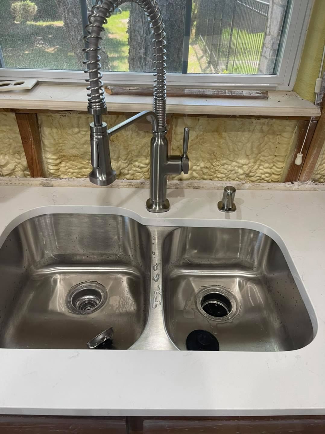 a stainless steel kitchen sink with a faucet and soap dispenser