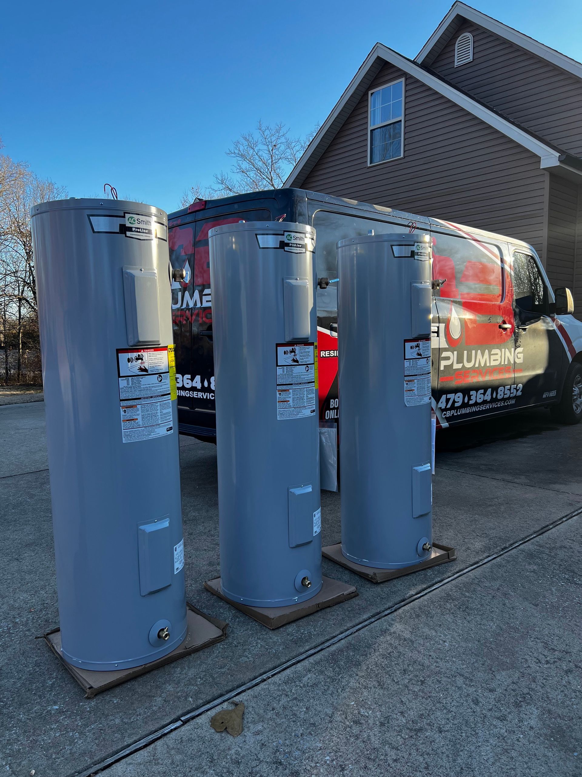 three water heaters are sitting on the sidewalk in front of a house