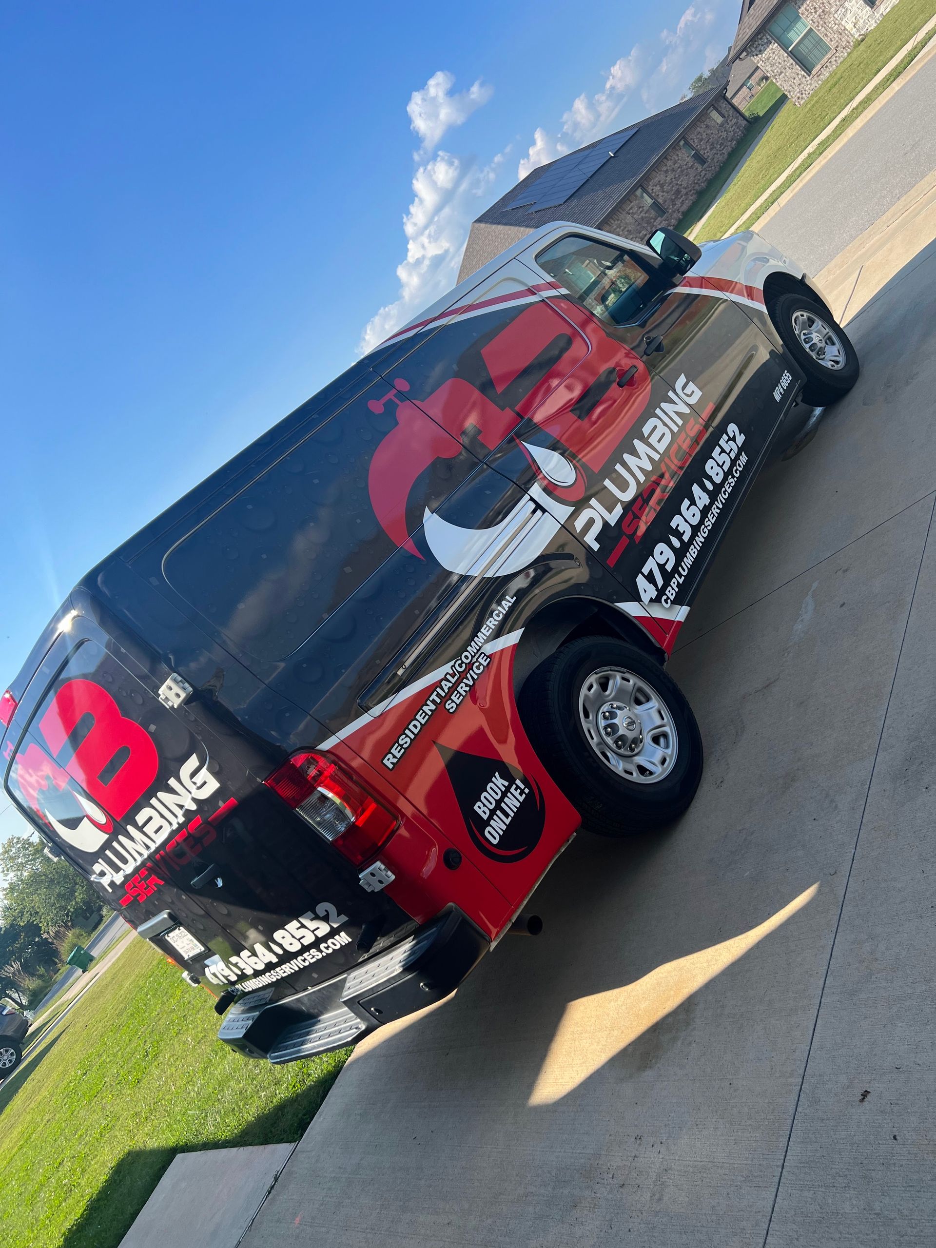 a red and black plumbing van is parked on the side of the road