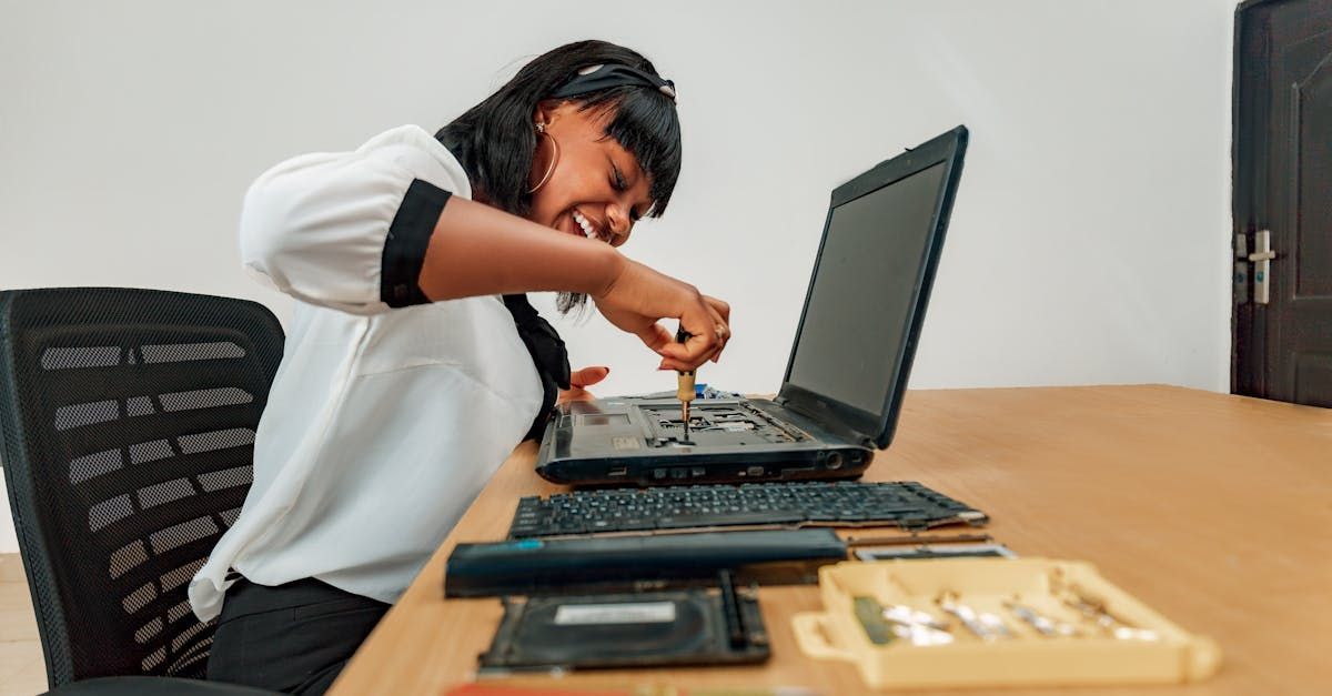 A woman is sitting at a desk working on a laptop computer.