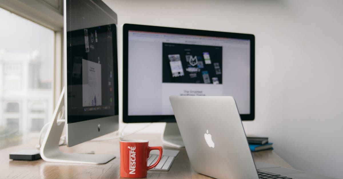 iMacs and a Mac Book sitting on a desk