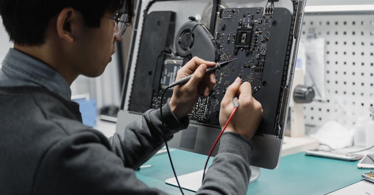 A man is fixing a computer monitor with a soldering iron.
