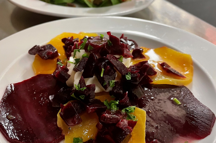 Beet salad on a white plate: red and yellow beets with cream and herbs.