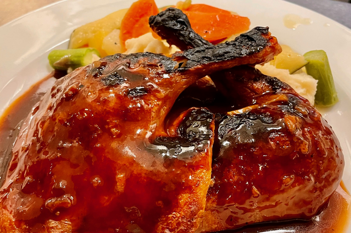 Grilled chicken with sauce, vegetables (carrots, asparagus, potatoes) on a white plate.
