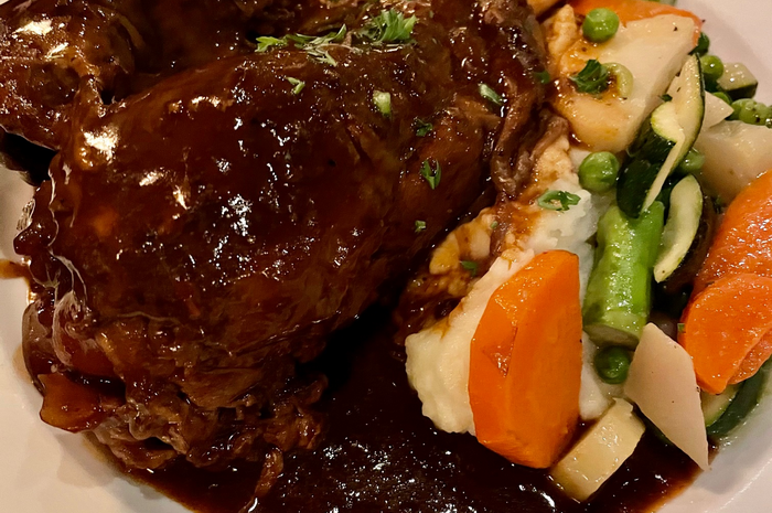 Braised meat in dark sauce with mashed potatoes and vegetables.