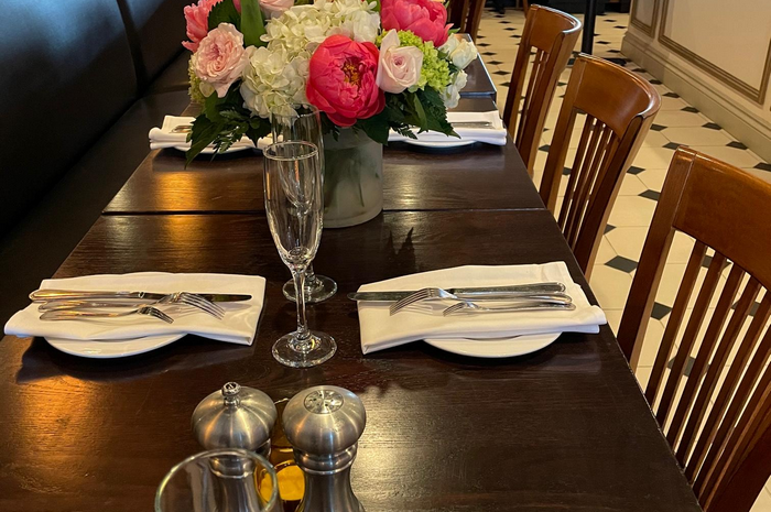 Dining table set for a meal with a flower arrangement and silverware.