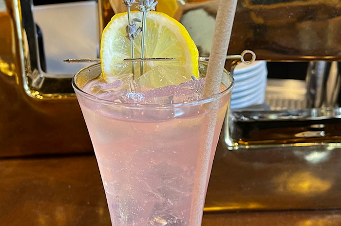 Pink cocktail with lemon slice and straw.