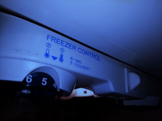 Close-up of a refrigerator freezer control dial with numbers and blue labels.