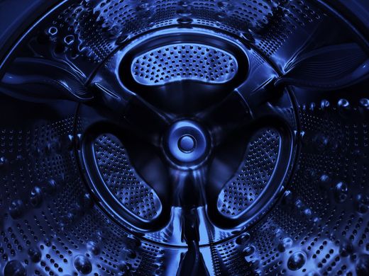Blue-lit view of a metallic washing machine drum with perforated panels and central hub