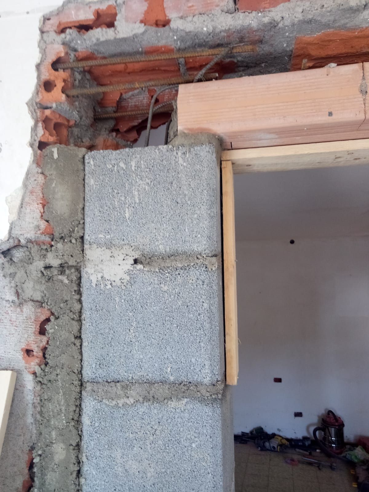 Costruzione di un portale con blocchi di cemento grigio, mattoni rossi e telaio in legno.