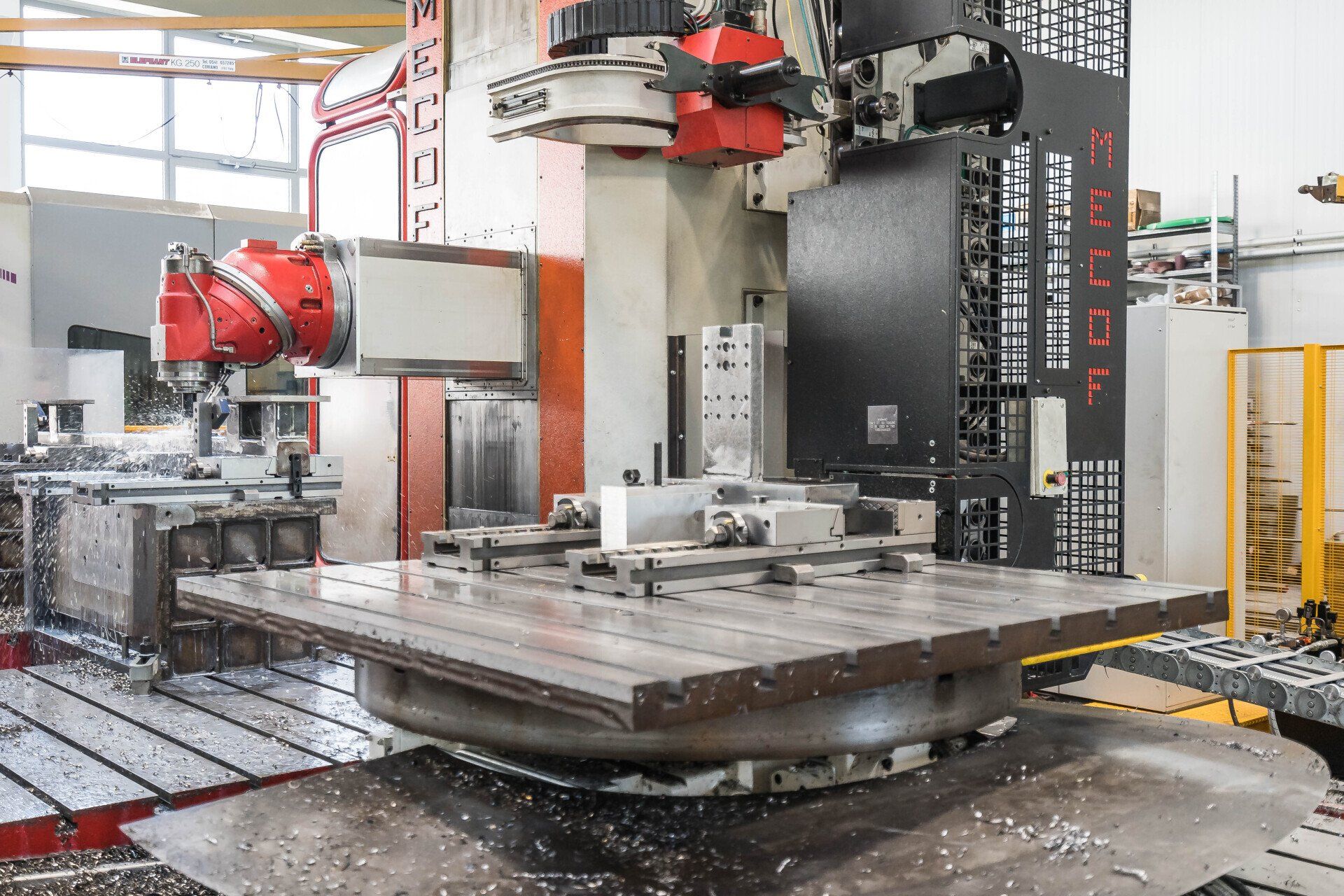 Fresatrice CNC industriale in un'officina, con piano di lavoro in metallo e componenti della macchina di colore rosso.