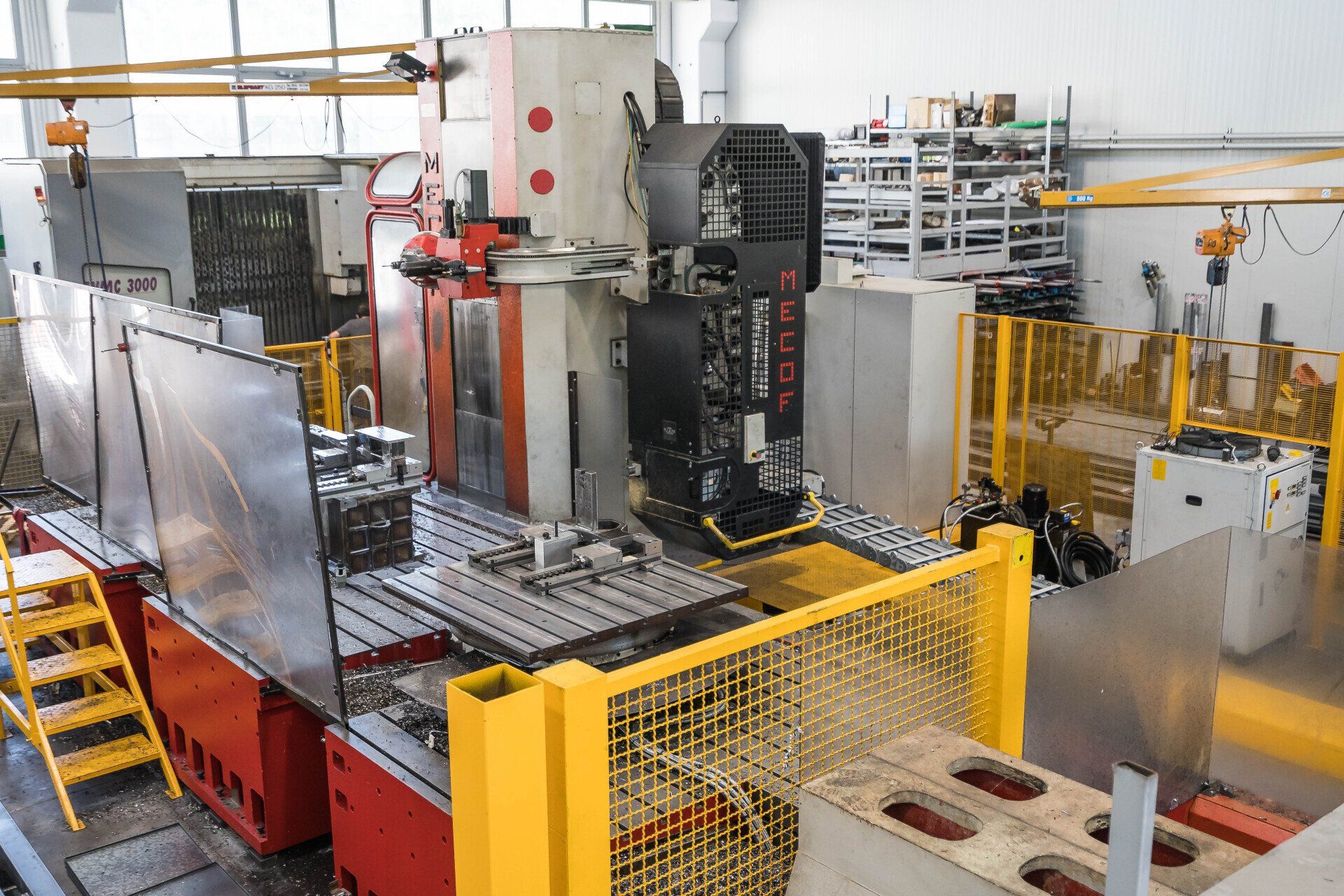 Macchinari industriali con recinzione di sicurezza gialla e pezzi metallici su una linea di produzione