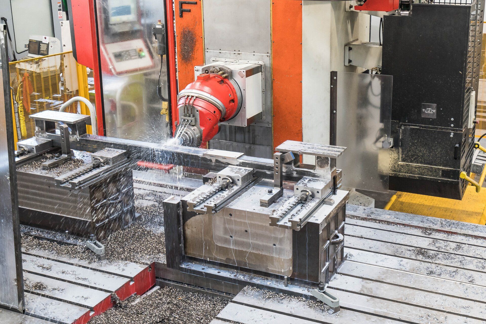 In un'officina industriale, una fresatrice CNC taglia un pezzo metallico con nebulizzazione di liquido refrigerante.