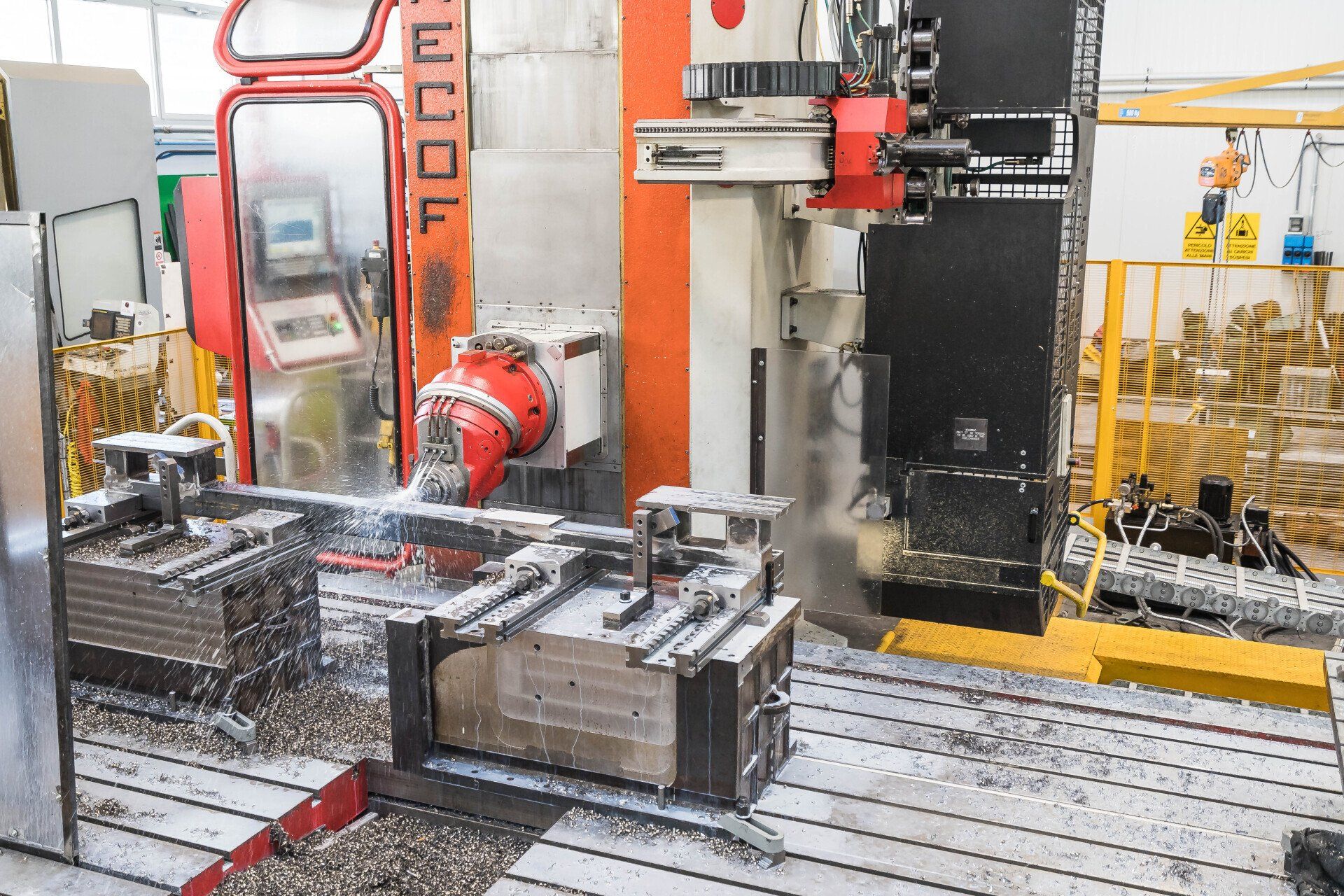 Braccio robotico industriale al lavoro accanto a componenti metallici in uno stabilimento di produzione.