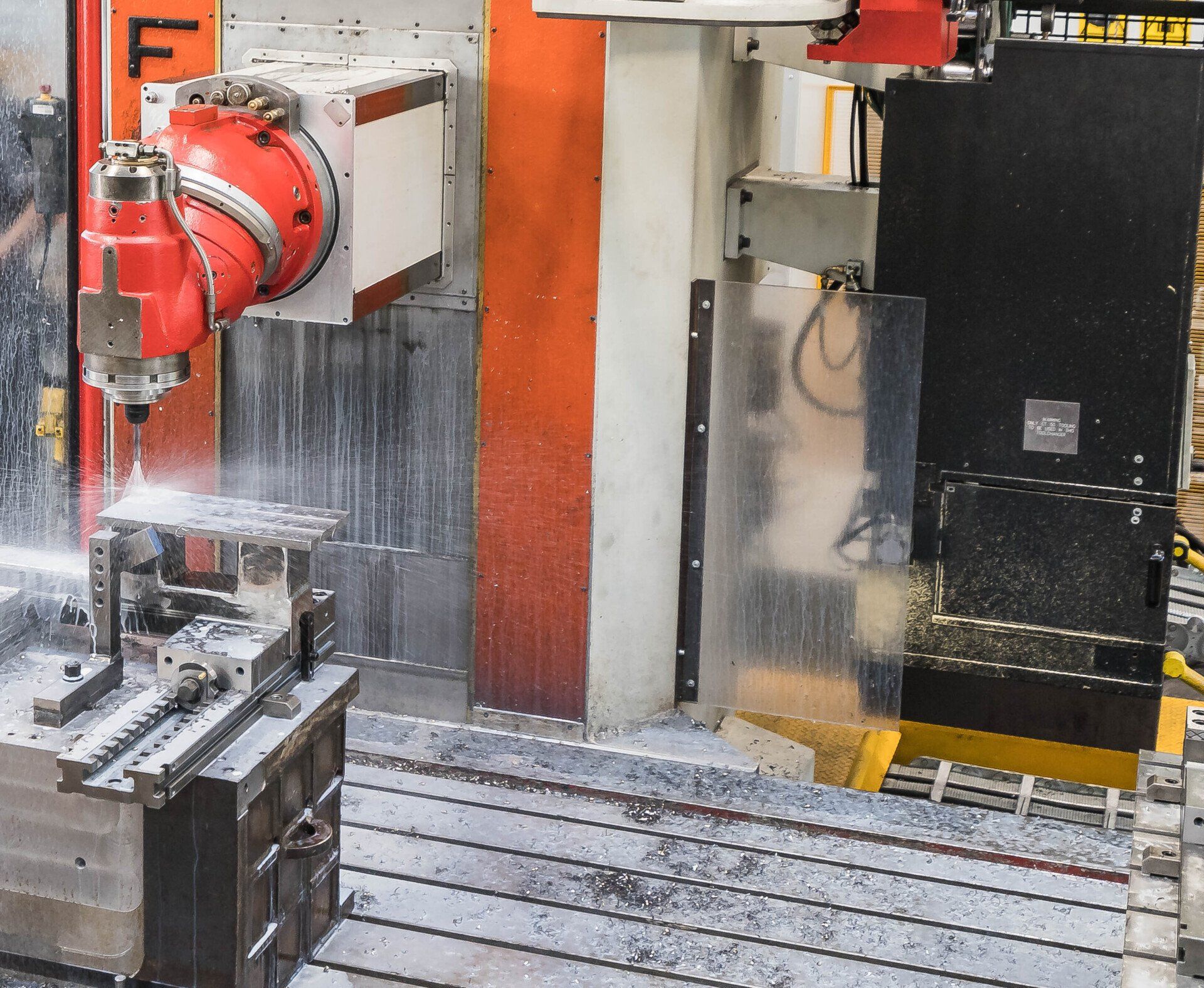 Fresatrice CNC per il taglio di metalli con nebulizzazione di liquido refrigerante in un'officina industriale.