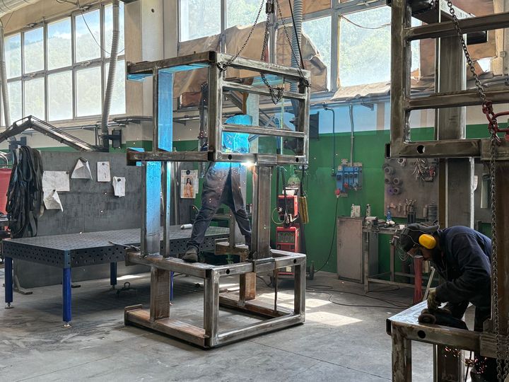 Operaio che aziona macchinari in un'officina industriale con telai e attrezzature metalliche.