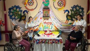 Two individuals in wheelchairs pose in front of a colorful