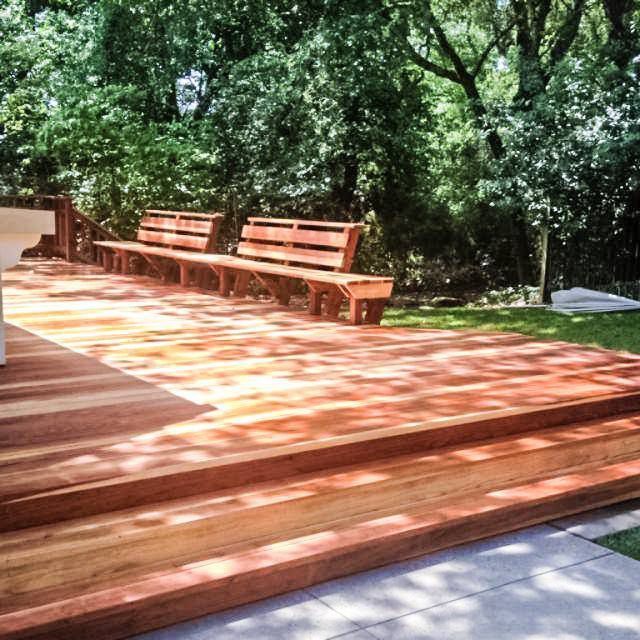 A wooden deck with benches and trees in the background