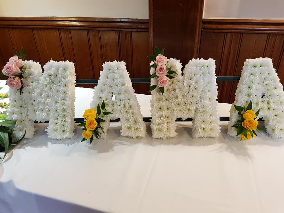 The word mama is made out of flowers on a table.