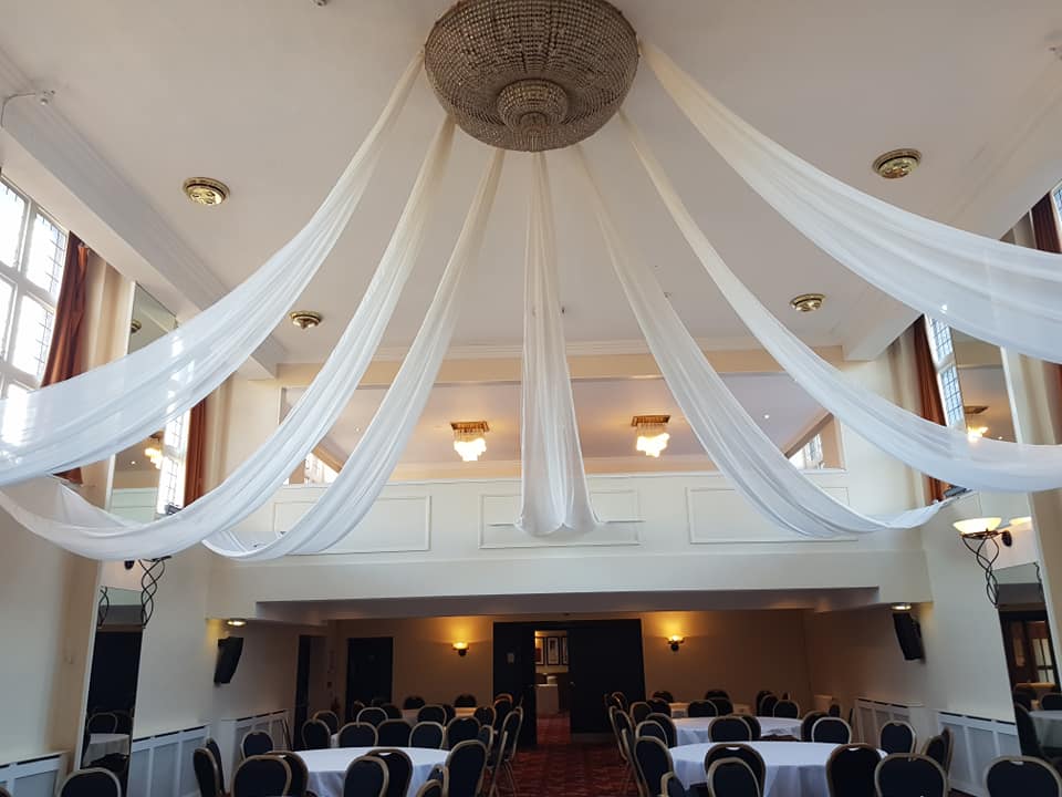 A large room with tables and chairs and a chandelier hanging from the ceiling.