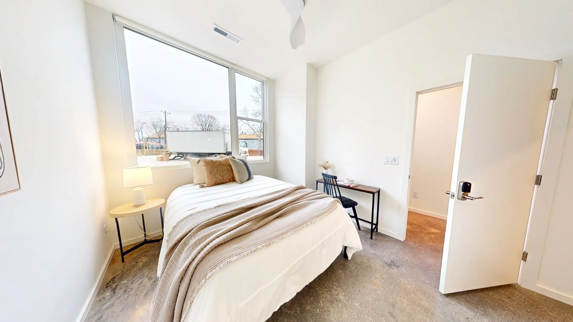 A bright, modern private bedroom in a Durham shared home featuring a workspace with a laptop, natura