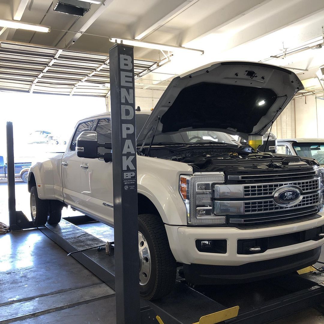 A white truck is on a lift with the hood open
