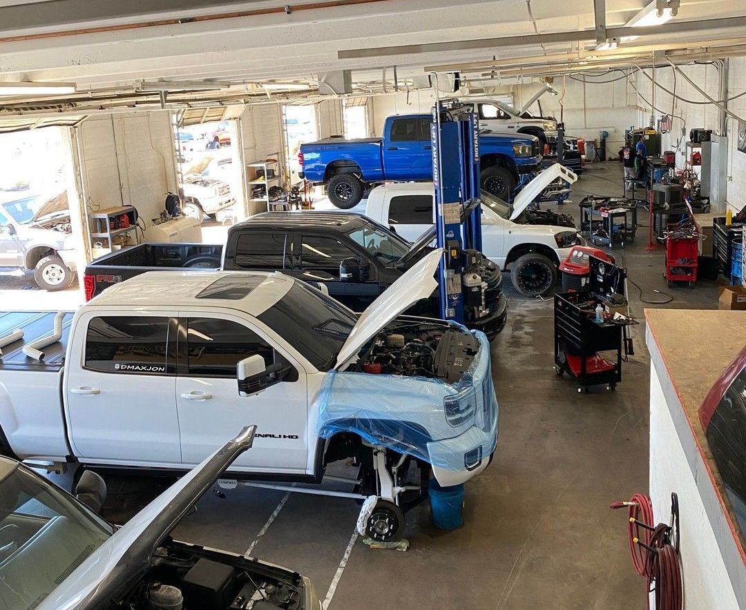 A row of trucks are parked in a garage with their hoods open.