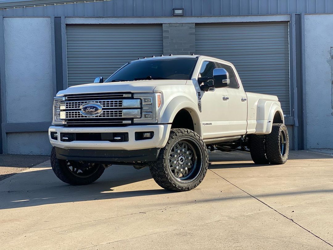 A white truck is parked in front of a garage door.