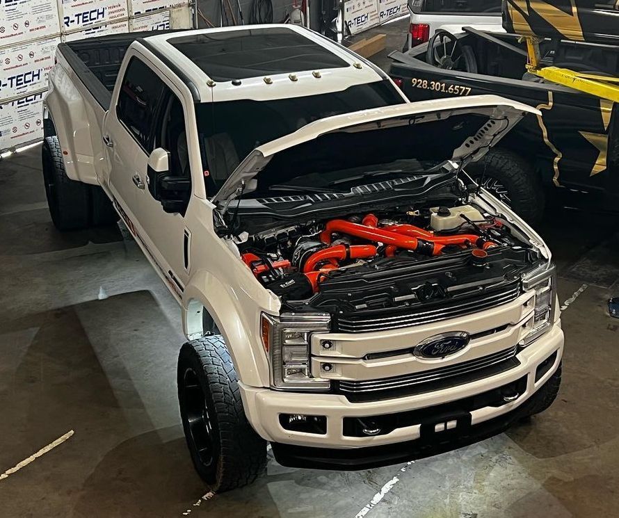 A white truck with the hood open is parked in a garage.