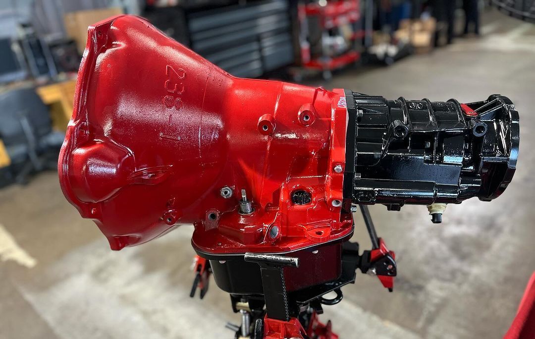 A red and black gearbox is sitting on a stand in a garage.