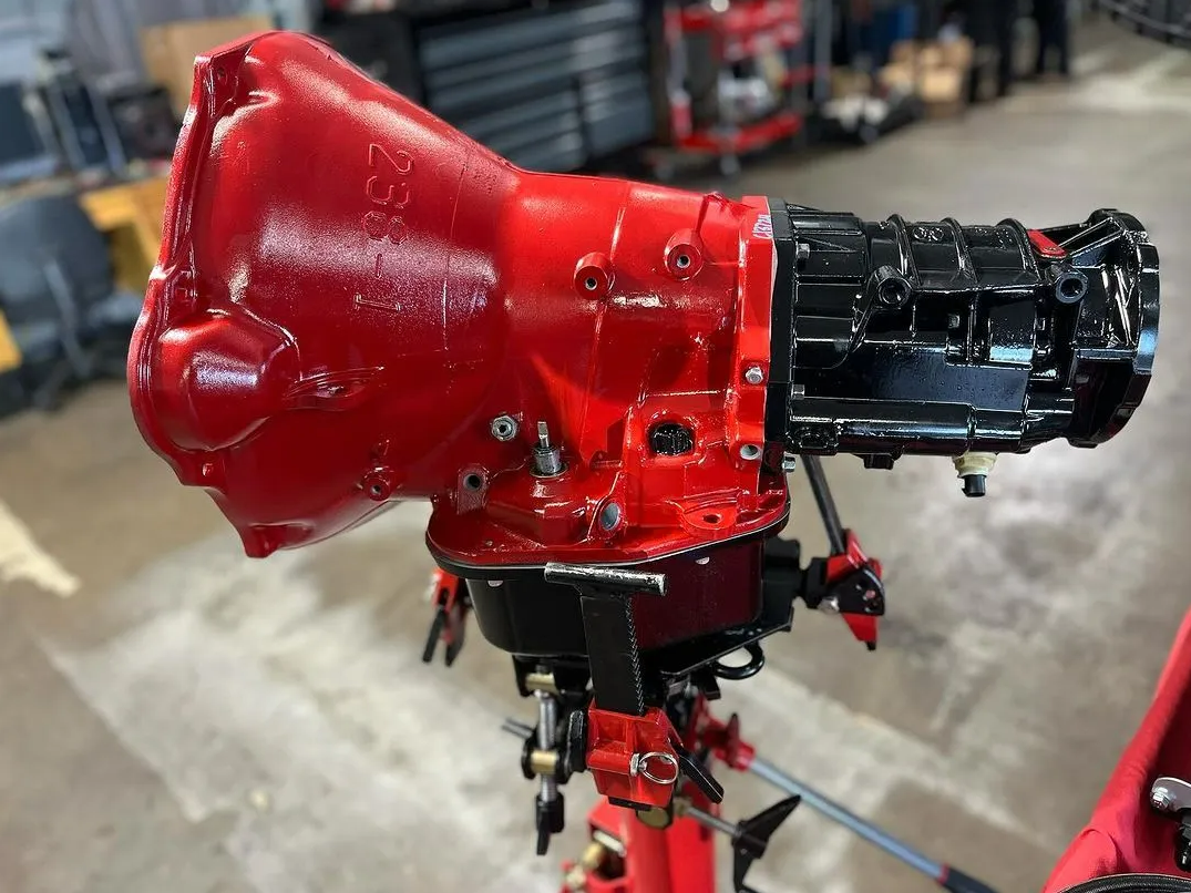 A red and black gearbox is sitting on a stand in a garage.