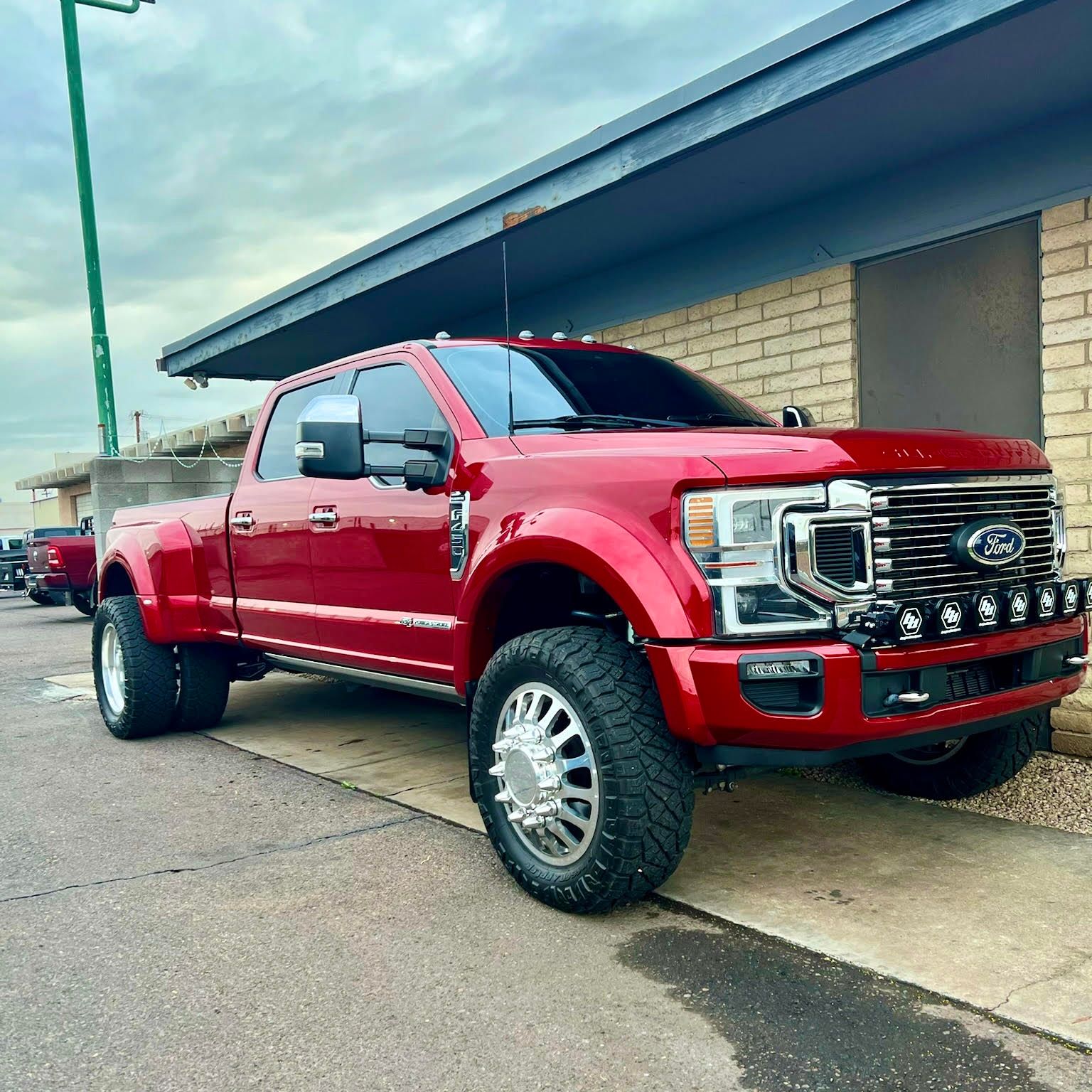 A red ford truck is parked in front of a brick building.