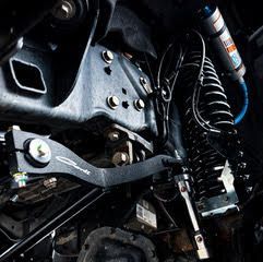 Close-up of a truck suspension system, showing shocks, springs, and control arms in a dark setting.