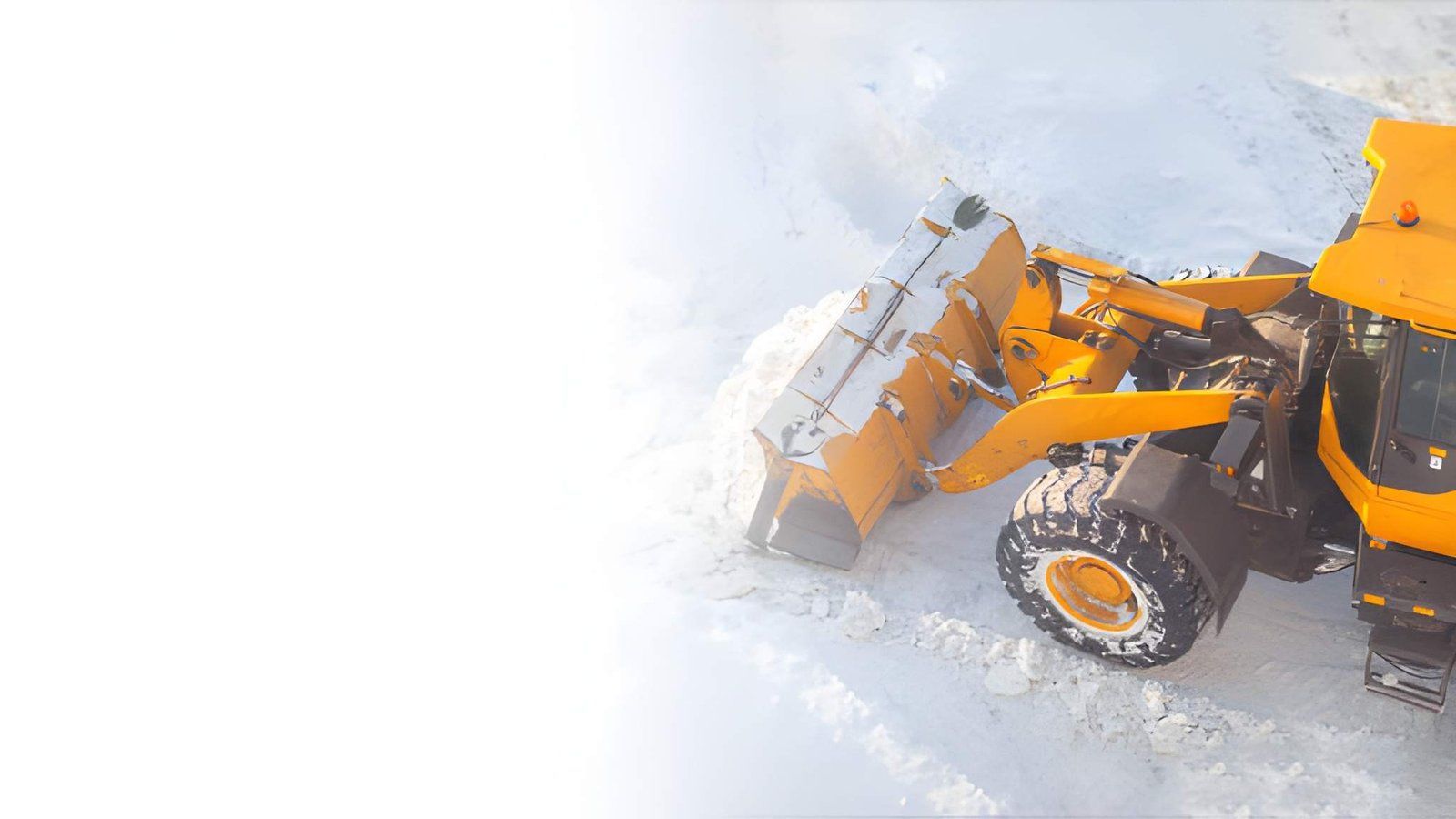 Orange front loader clearing snow on a snowy road, with a bright overexposed background.