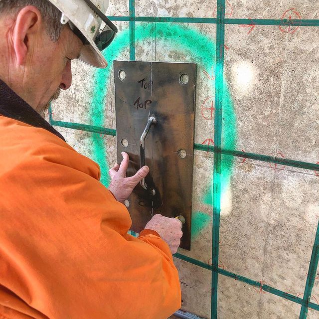 A man wearing a hard hat is working on a wall