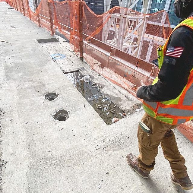 A construction worker wearing a safety vest with an american flag on his sleeve